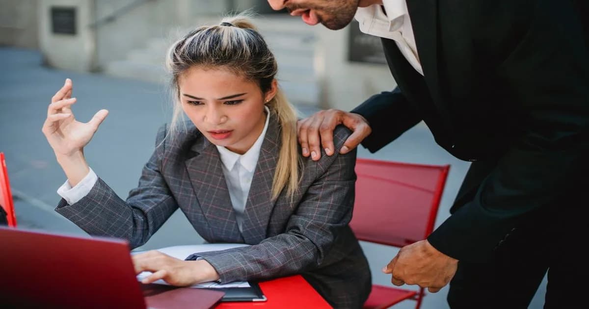 Profesional en reunión de trabajo mirando su teléfono mientras sus colegas esperan, representando falta de atención y confiabilidad