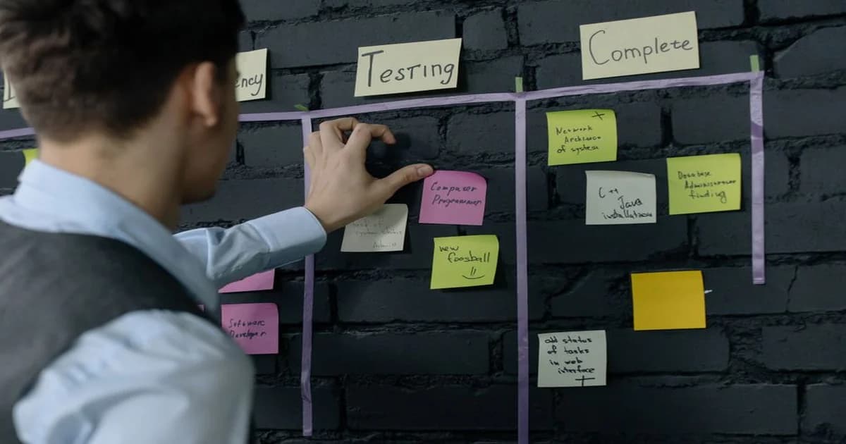 Gerente revisando tablero de proyectos en oficina moderna con equipo al fondo