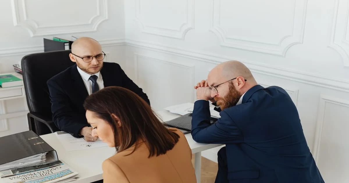 Gerente conversando con dos colaboradores en sala de reuniones, ambiente de mentoría profesional