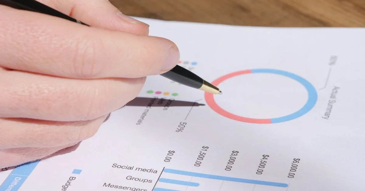 Gerente revisando tablas de presupuesto operativo en una laptop con documentos financieros sobre el escritorio