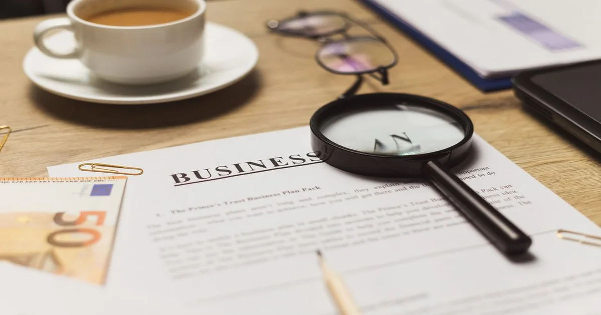 Gerente revisando una propuesta comercial impresa sobre una mesa de reuniones con laptop abierta