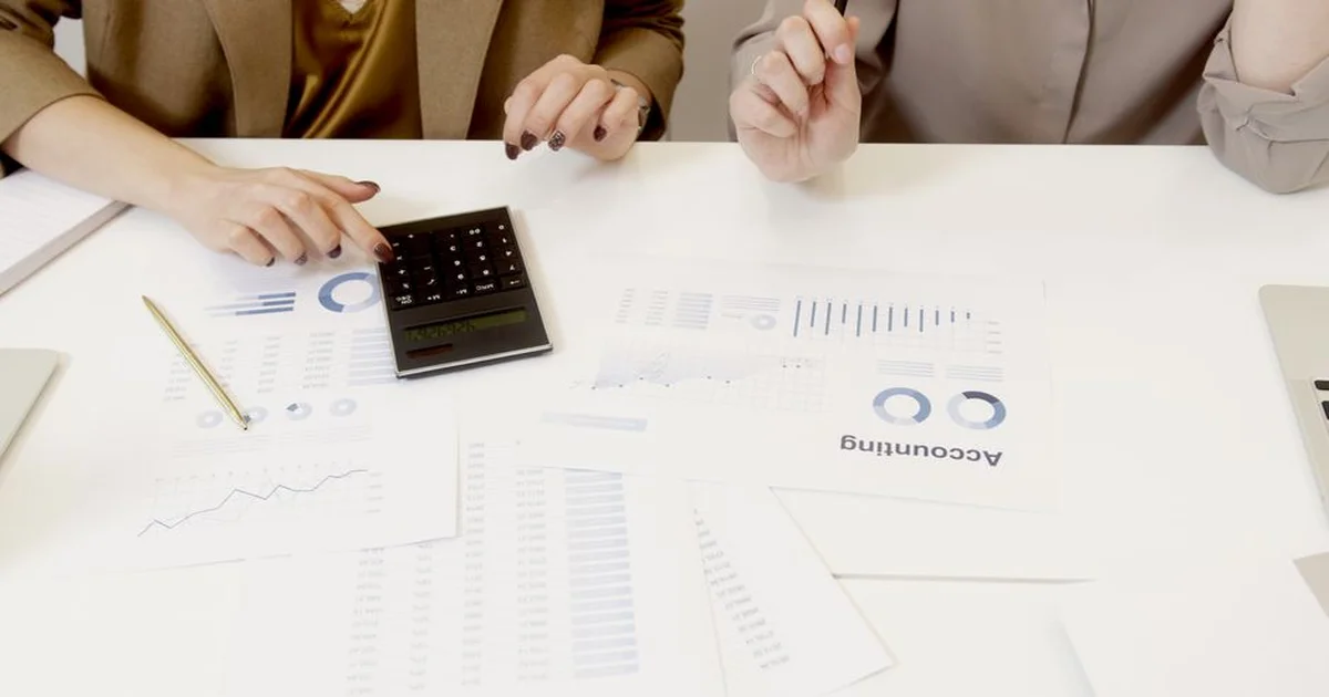 Gerente revisando un estado de resultados impreso sobre un escritorio con laptop y calculadora
