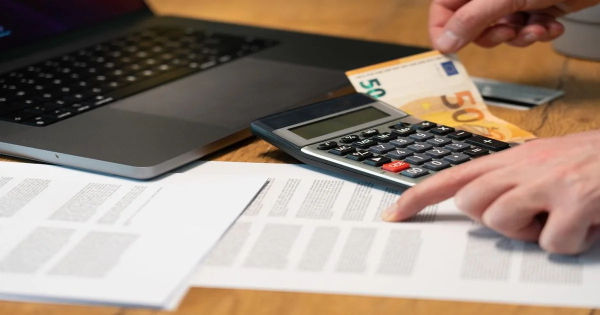 Gerente revisando una cotización impresa sobre un escritorio con laptop y calculadora