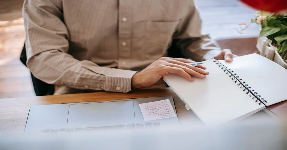 Gerente revisando en su laptop una lista de tareas mientras organiza su semana en una oficina luminosa