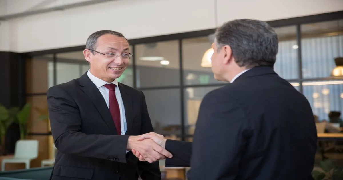 Dos personas en reunión de retroalimentación; notas claras, se revisan hechos e impacto y se acuerda el próximo paso
