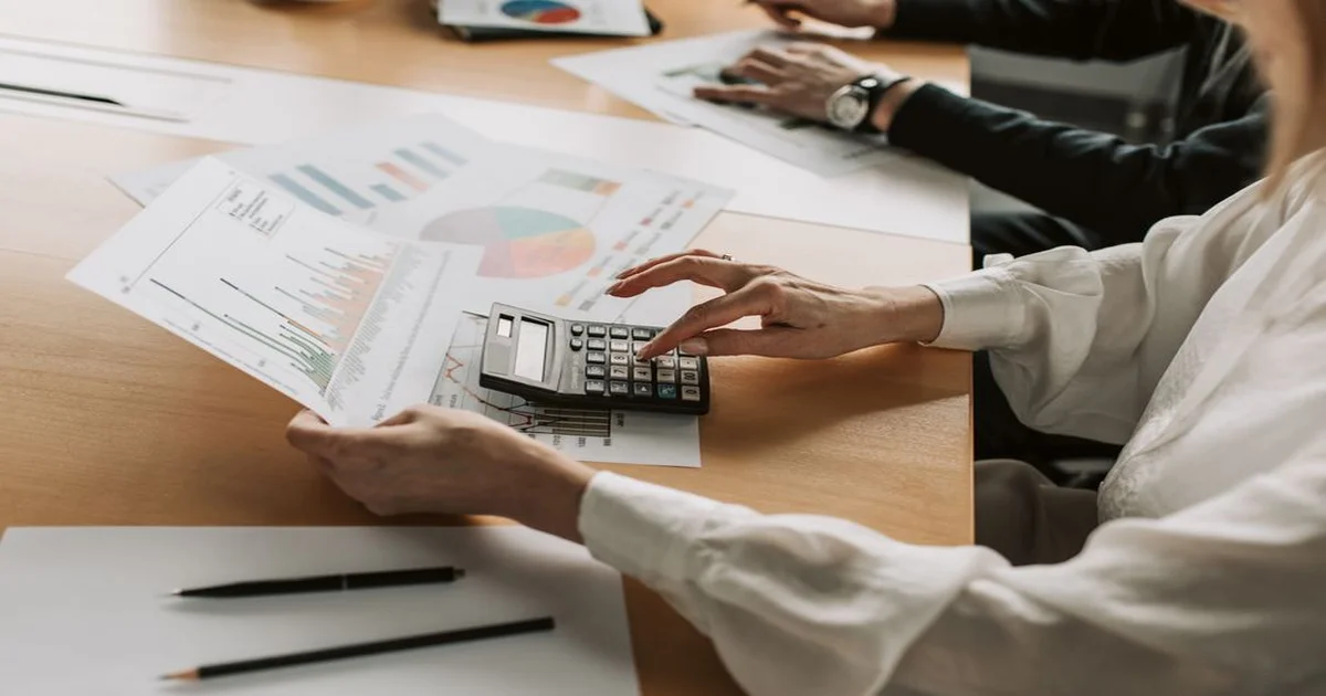 Gerente presentando a un CFO tablas comparativas de ahorro y riesgo, con gráficos de servicio y retención en una sala de reuniones