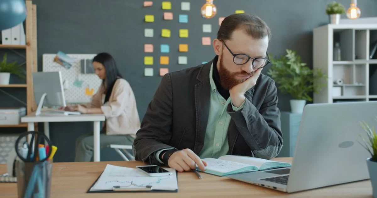 Gerente revisando métricas de asistencia de su equipo en una pantalla de computadora en oficina moderna