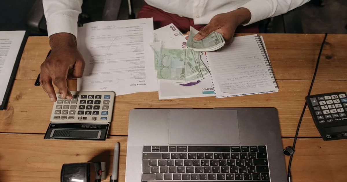 Gerente revisando reporte de cuentas por cobrar en laptop con gráficas financieras sobre escritorio de oficina