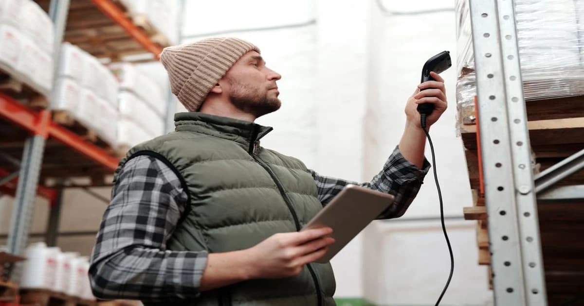 Gerente revisando estantes de almacén con tablet y datos de inventario en pantalla